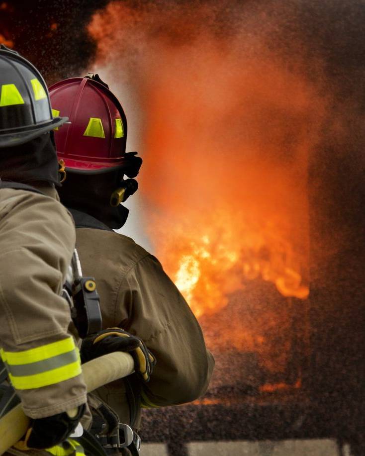 Firefighters directing a hose at a burning building
