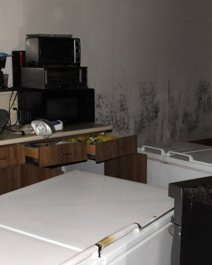 Break room with overturned refrigerators and mold above the flood line