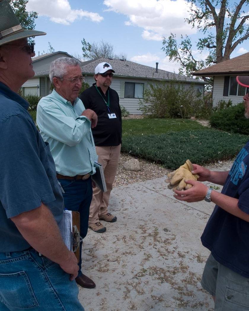 Homeowner showing storm damage to assessors outside his house