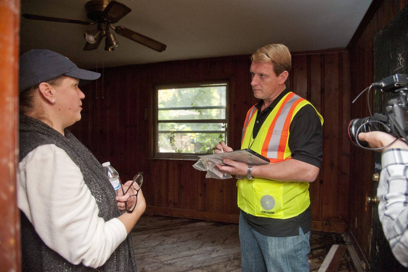 Inspector taking notes with a homeowner in a flood-damaged room